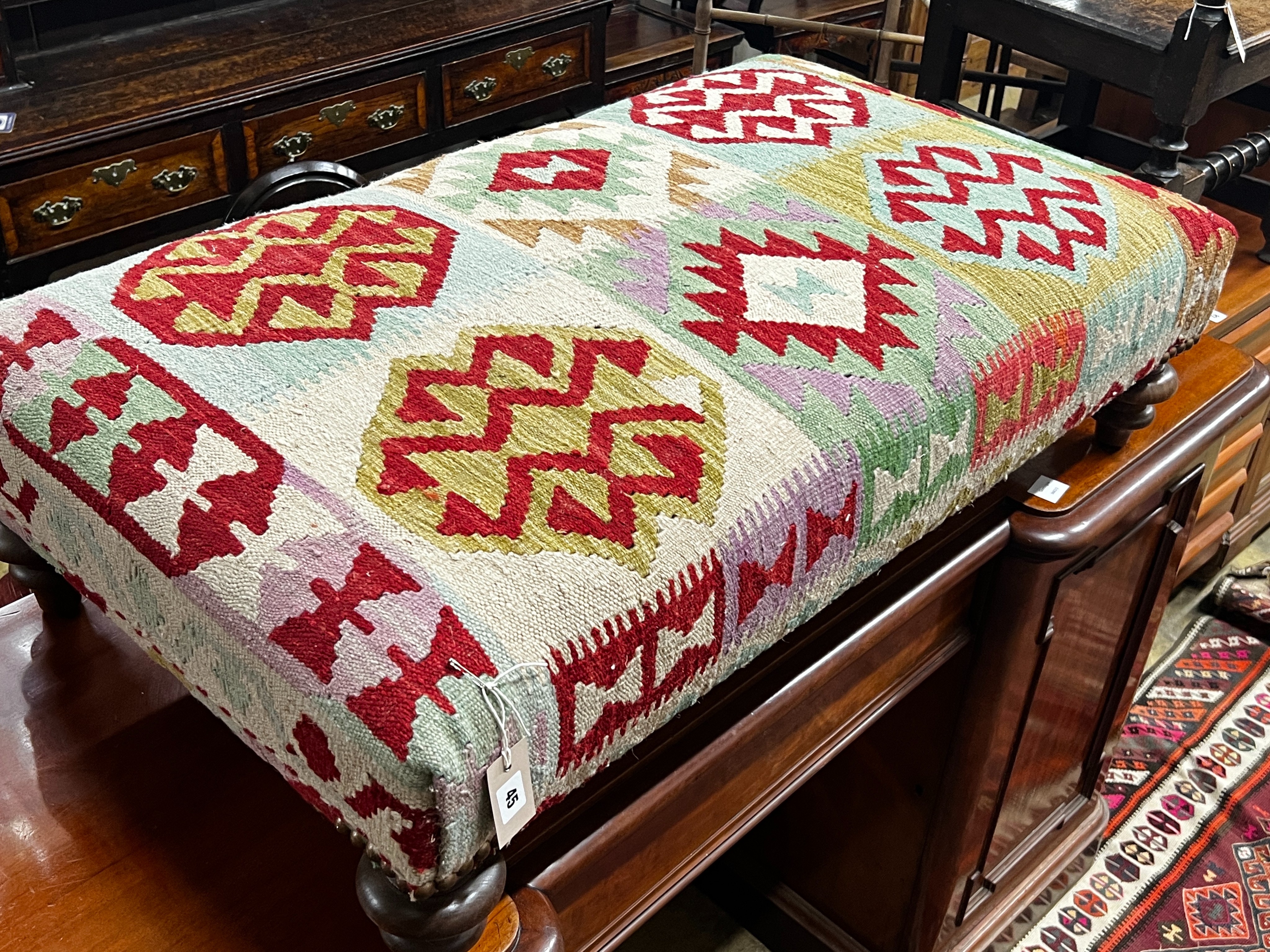 A large contemporary rectangular polychrome Kilim footstool on turned feet, length 108cm, depth 64cm, height 30cm